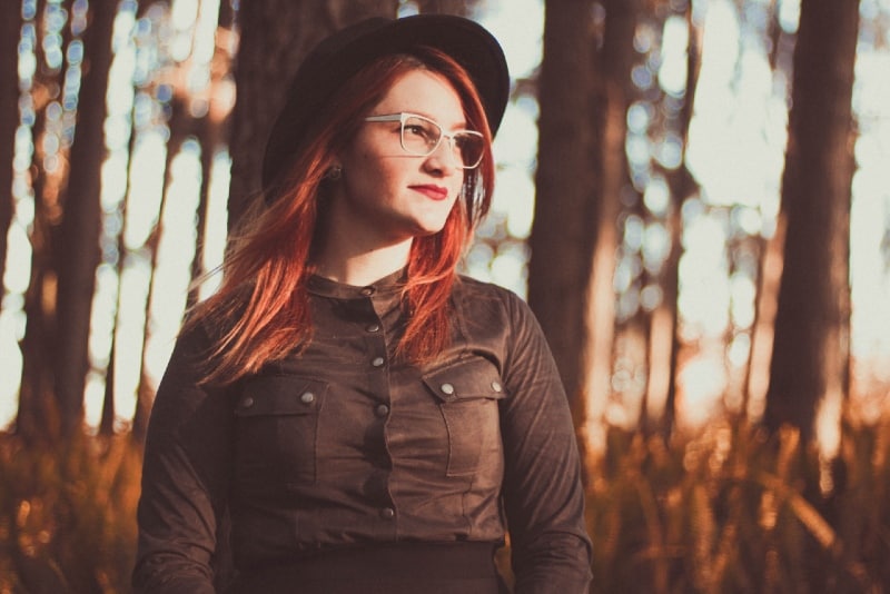 woman with black hat standing near trees