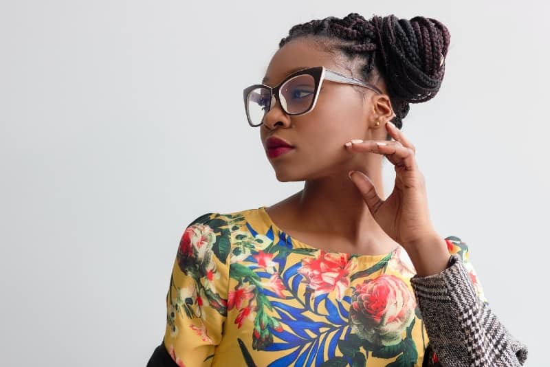 woman in yellow floral top standing near wall