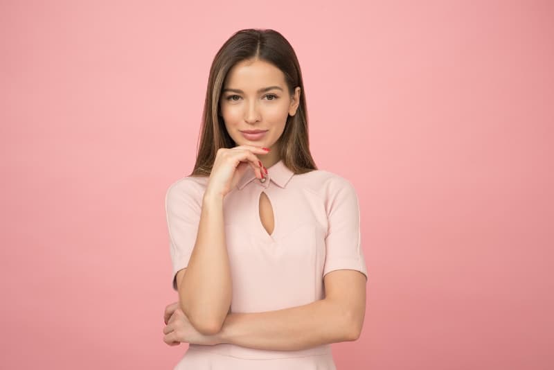 mujer con top rosa de pie cerca de una pared rosa