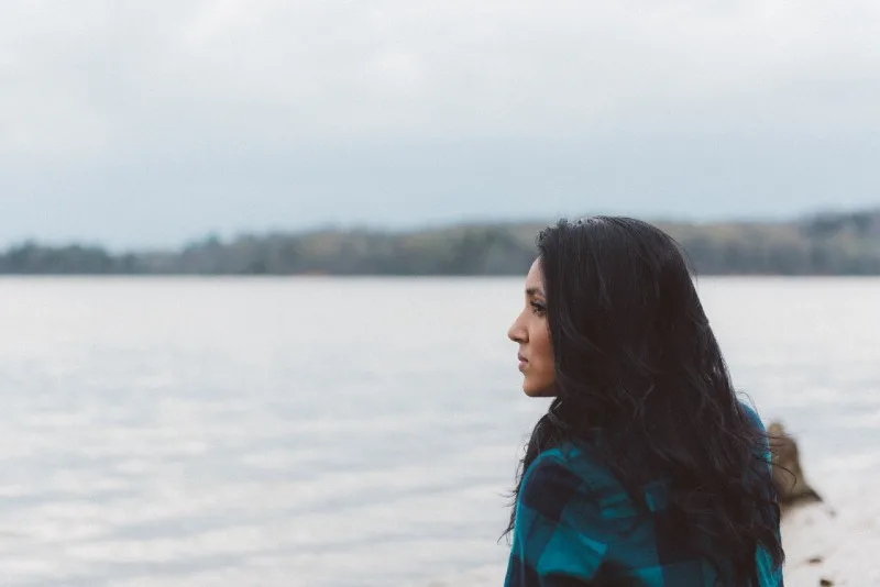 black haired woman standing near water