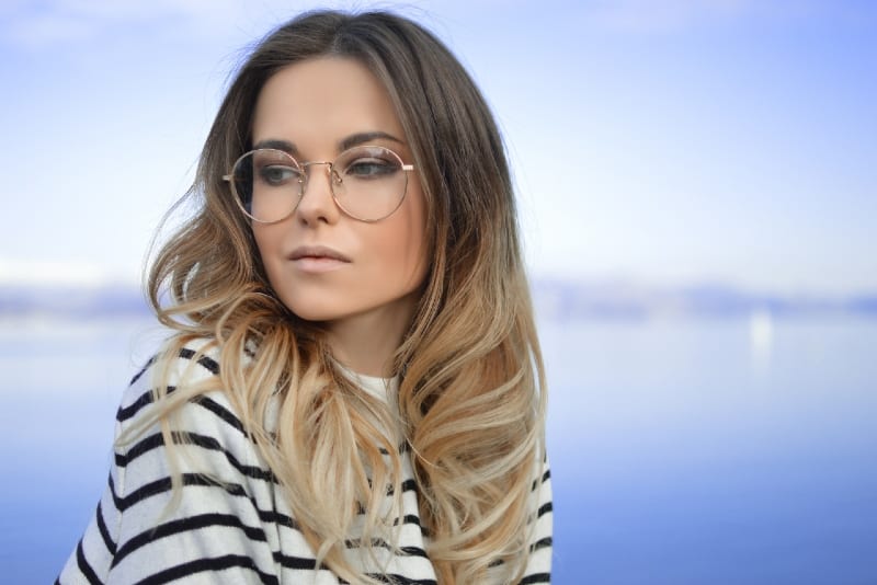 woman with round eyeglasses standing near water