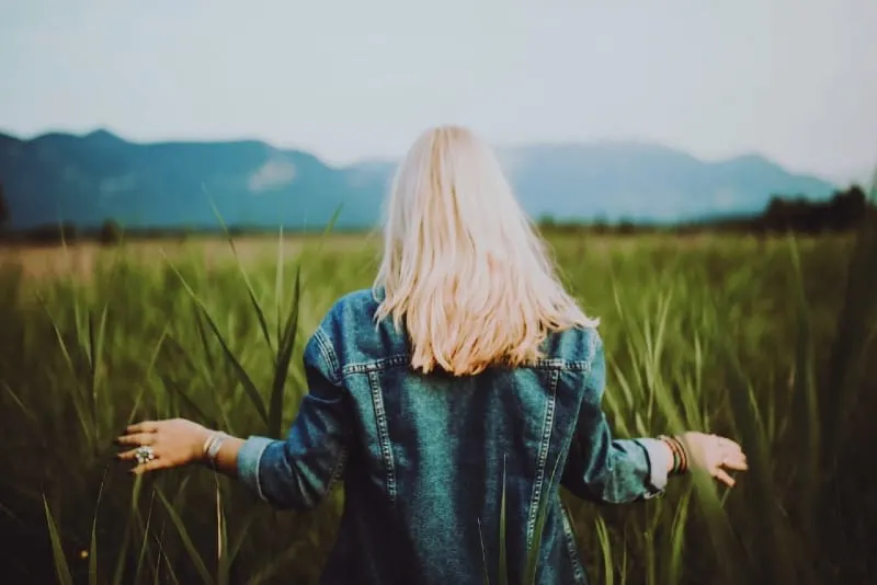blonde woman in green jacket standing on green field