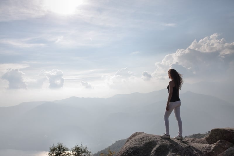 donna in piedi sulla roccia che guarda la montagna