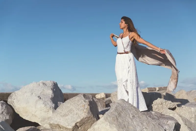 woman in white dress standing on rocks during daytime