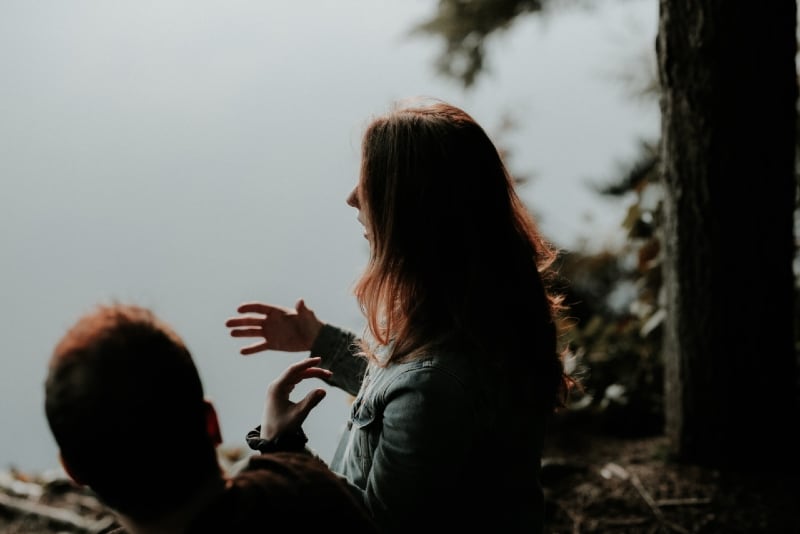 woman talking to man while sitting near water