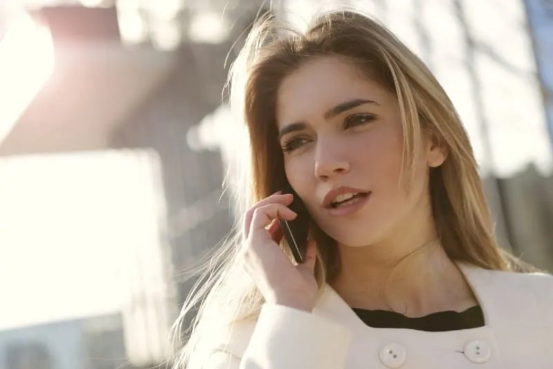 blonde woman in white coat talking on the phone