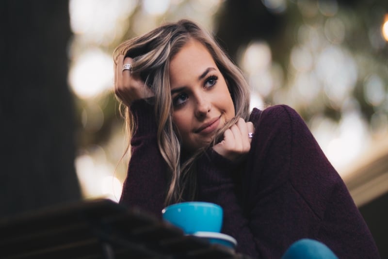 mujer con top morado tocándose el pelo