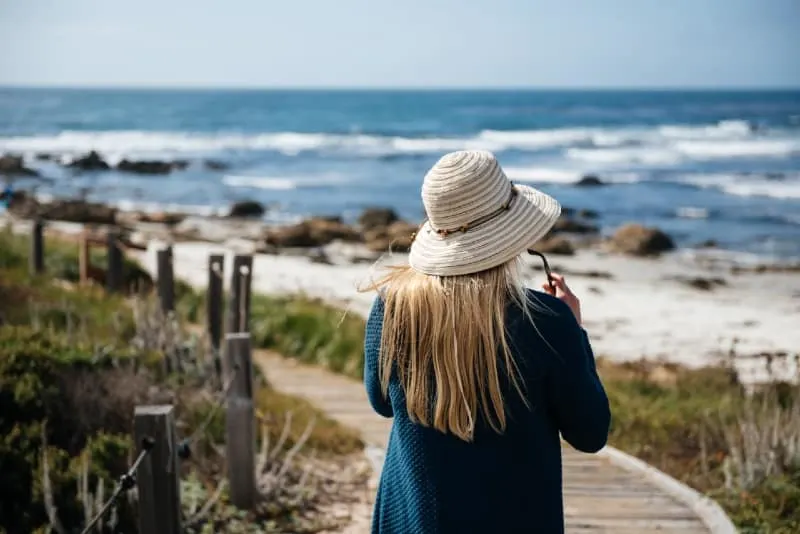 woman with hat walking on seashore