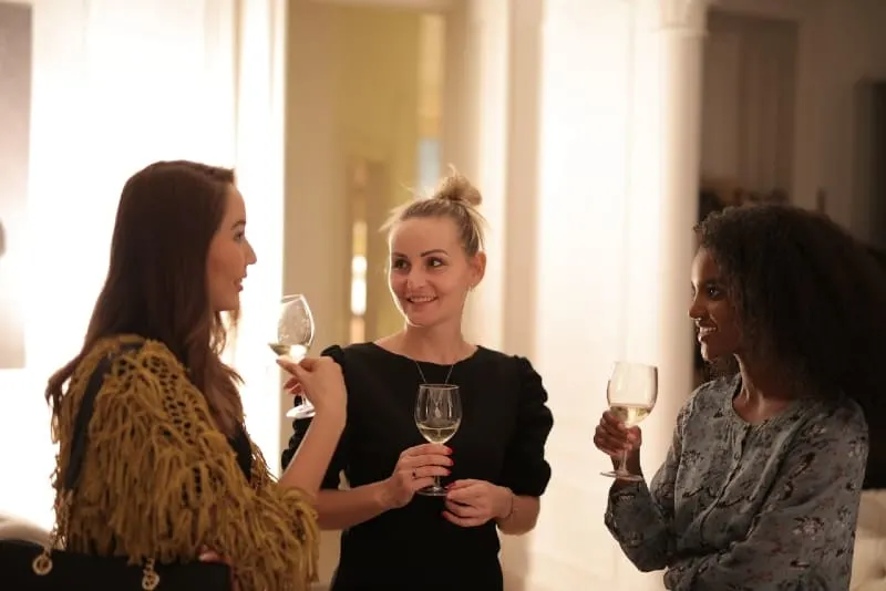 three women holding glasses of wine and talking