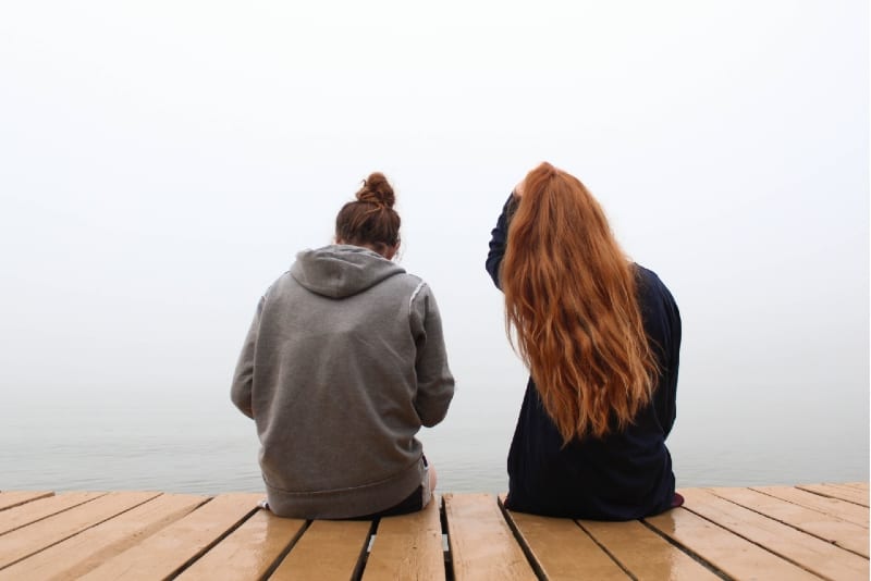 due donne sedute su un pontile di legno a parlare