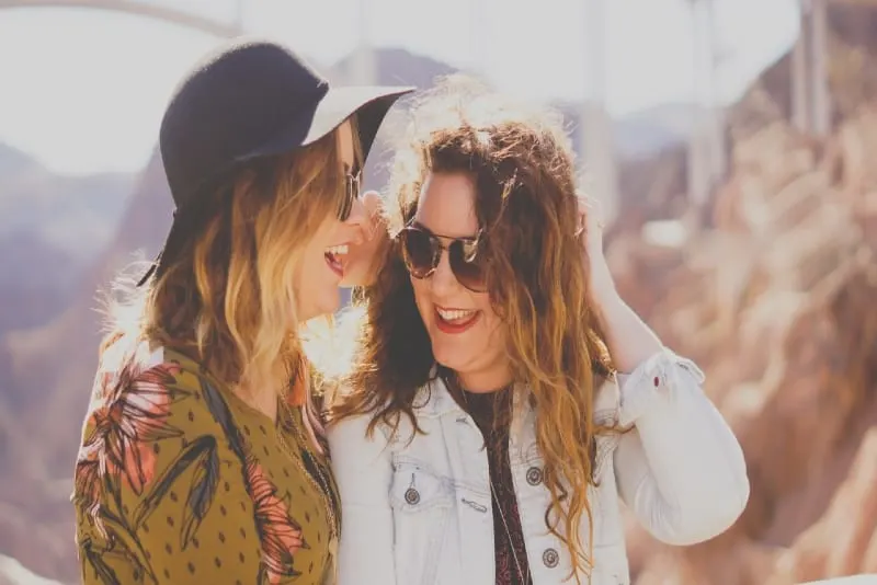 two smiling women with sunglasses standing outdoor