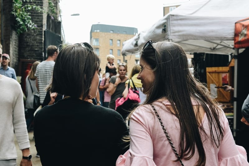 dos mujeres caminando cerca de puestos de comida