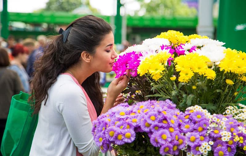 mulher jovem a comprar flores no mercado enquanto as cheira