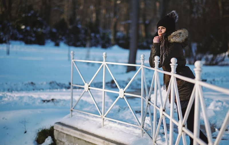 mulher jovem de pé na ponte num parque de inverno