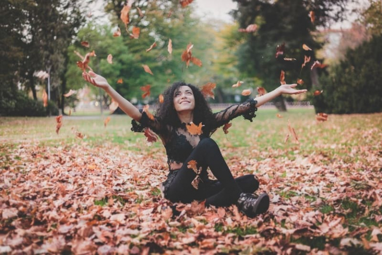 smiling woman in black top sitting on dried leaves
