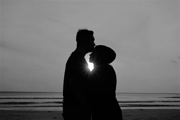 silhueta de um homem e de uma mulher de pé na praia