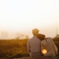 man and woman sitting near grass field