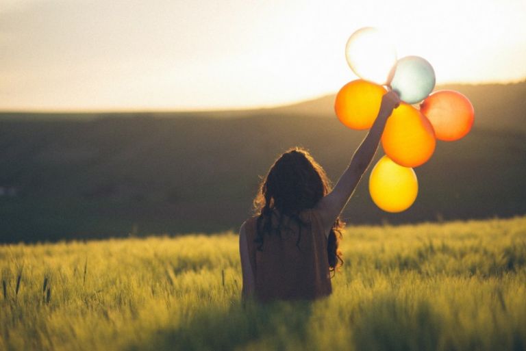 woman holding balloons in the field