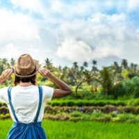 mulher com chapéu a olhar para um campo verde