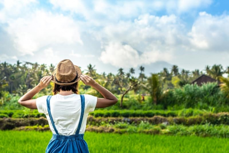 woman with hat looking at green field