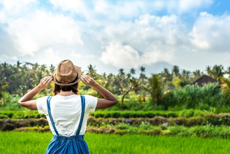 woman with hat looking at green field