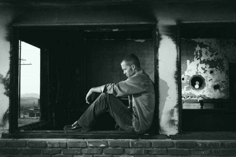 sad man sitting on window pane