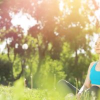 mulher a meditar sentada no chão, ao ar livre