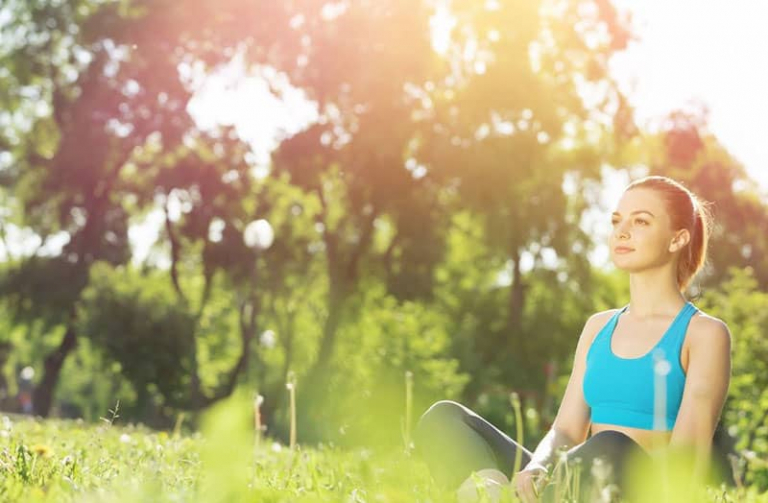 woman meditating while sitting on the ground outdoors