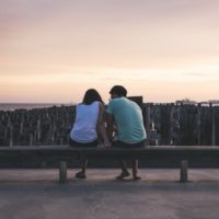 hombre y mujer sentados en un banco cerca del agua