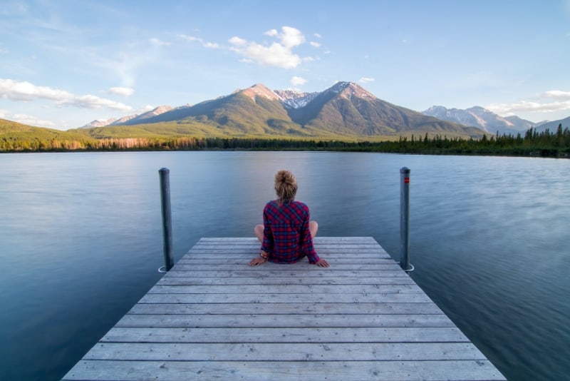 woman sitting on dock looking at lake