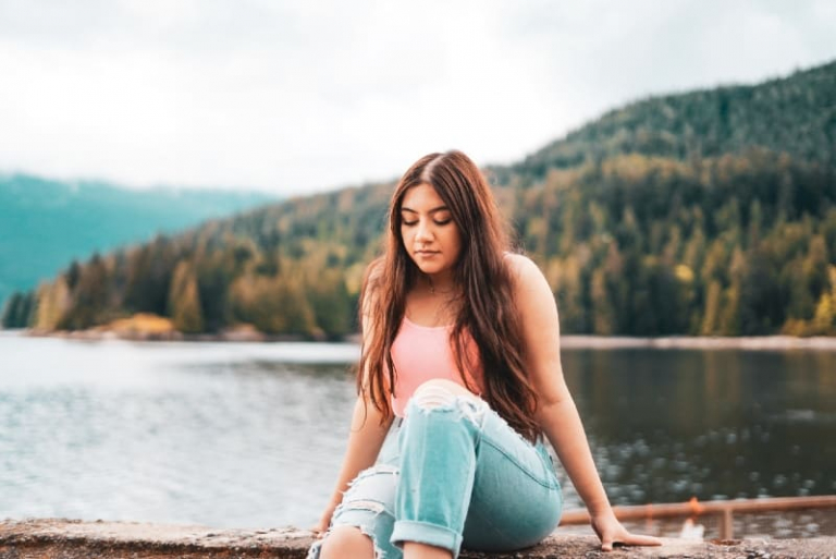 woman in blue denim jeans sitting on wooden dock