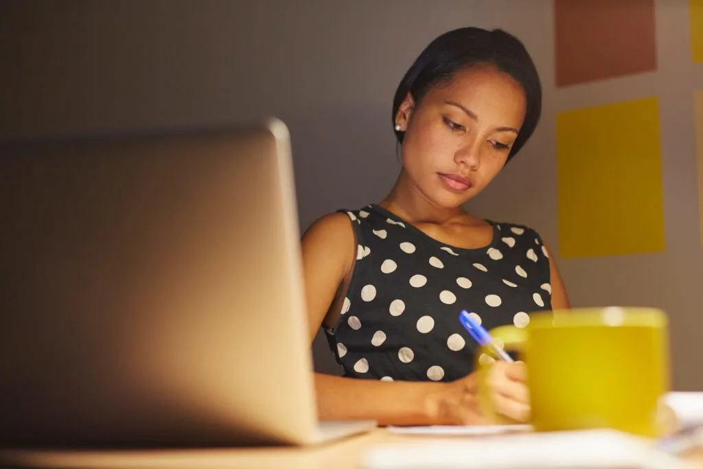 A young beautiful girl writes notes while sitting at the desk