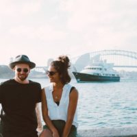 smiling man and woman sitting on bench beside water