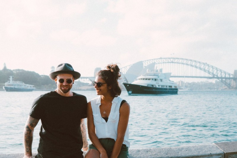 smiling man and woman sitting on bench beside water