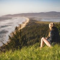 mujer sentada en una colina mirando al océano