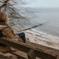 woman sitting on bench looking at water