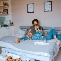 woman feeding man with pizza while lying in bed