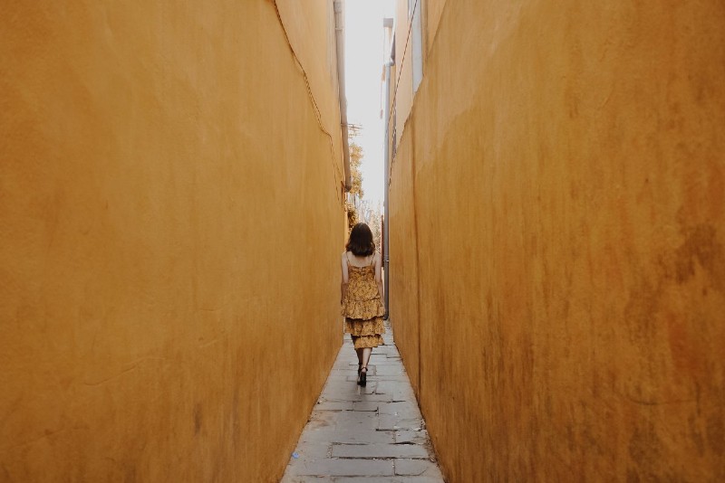 donna in abito giallo che cammina lungo un sentiero