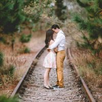 un hombre y una mujer abrazados junto a las vías del tren