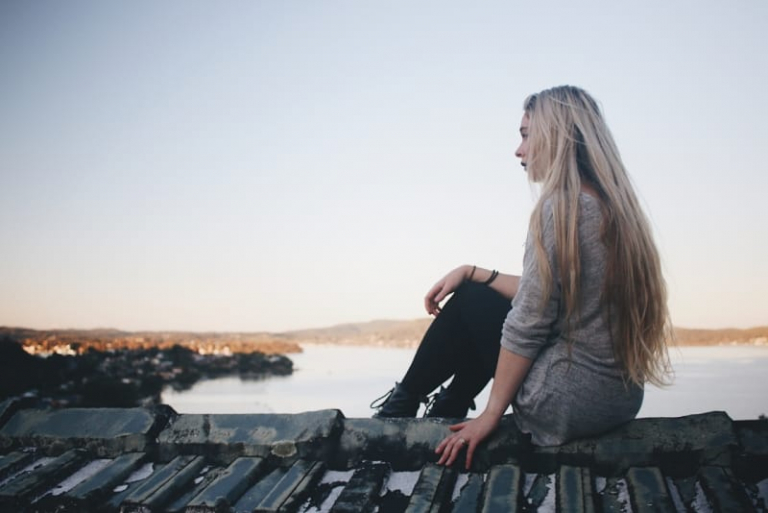 blonde woman in gray top sitting on rooftop