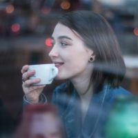 mujer con taza blanca sentada al aire libre