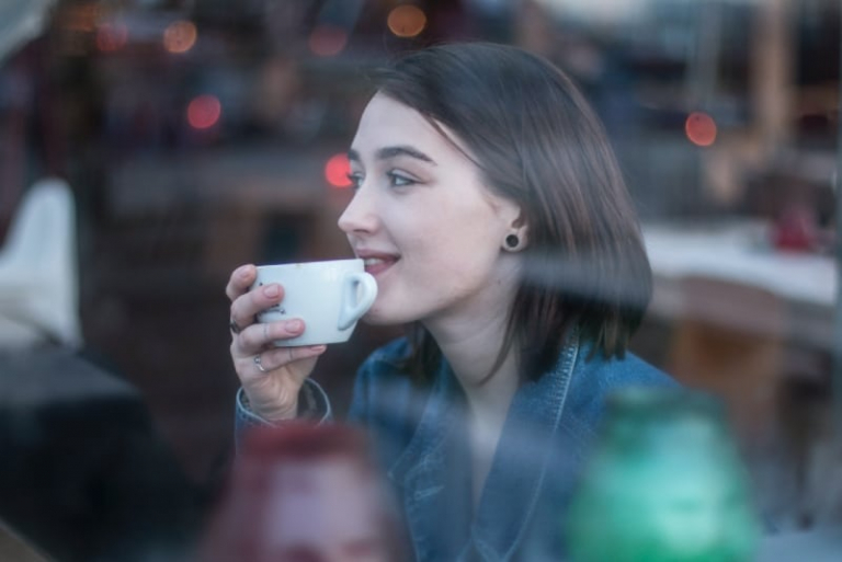 donna che tiene una tazza bianca seduta all'aperto