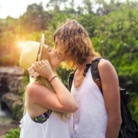 donna con cappello e uomo che si baciano all'aperto