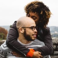 woman kissing man's head while standing outdoor