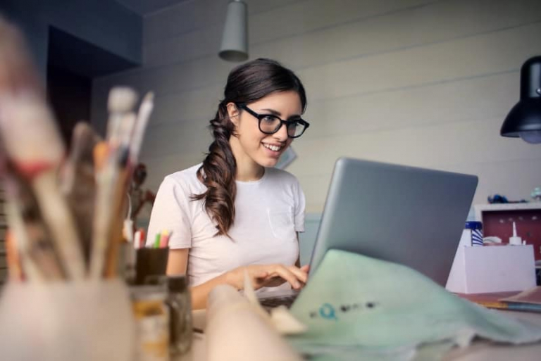 woman with eyeglasses using laptop while sitting at table