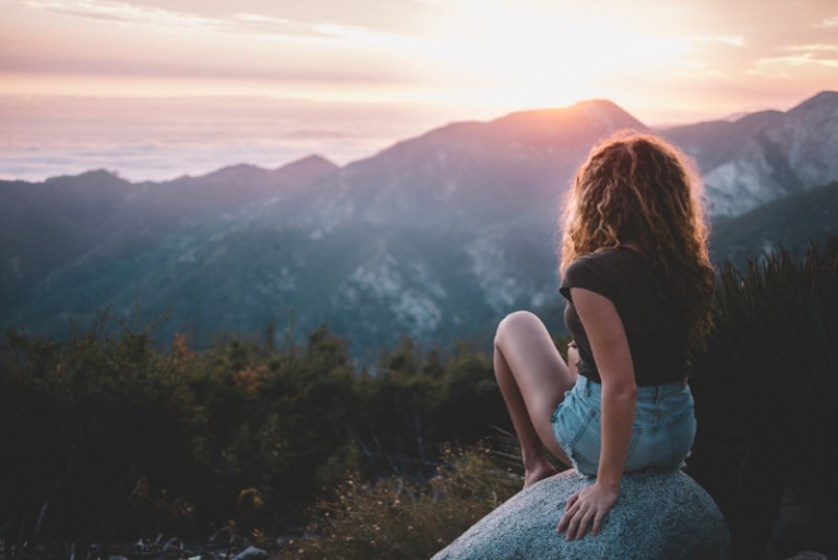 woman sitting on rock looking at mountain