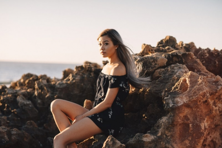 woman in black floral dress sitting on rock