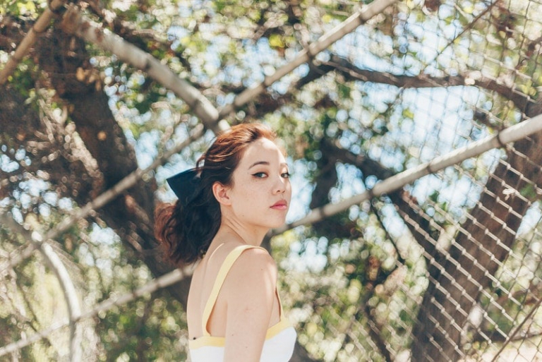 a serious Japanese woman stands by the fence