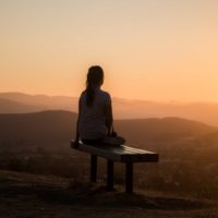 woman sitting on bench looking at mountain