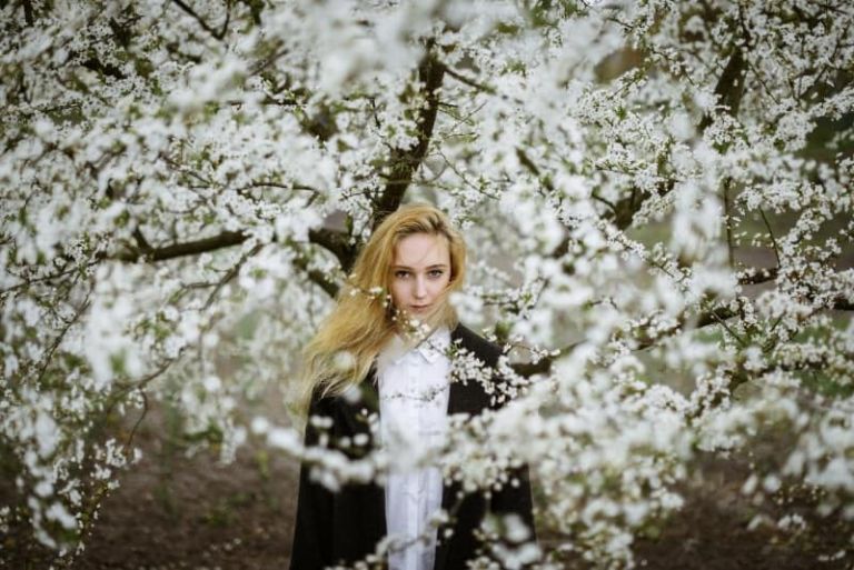 mujer con camisa blanca cerca de un árbol